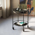 Matte black powder-coated Serving Table with curved steel rods and four wheels on a light floor.