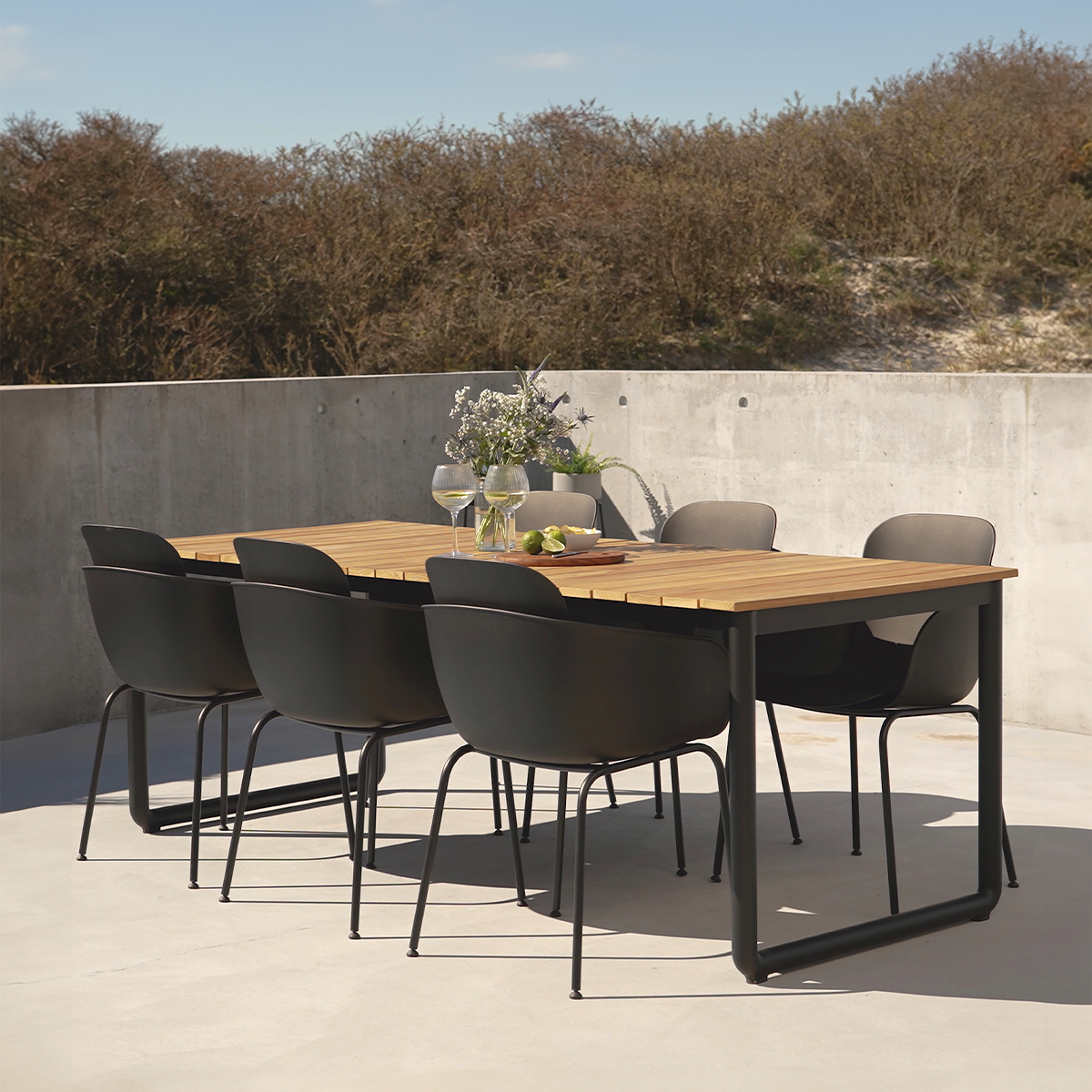 Outdoor patio chair with two-tone shells and black powder-coated steel frame in a natural setting.