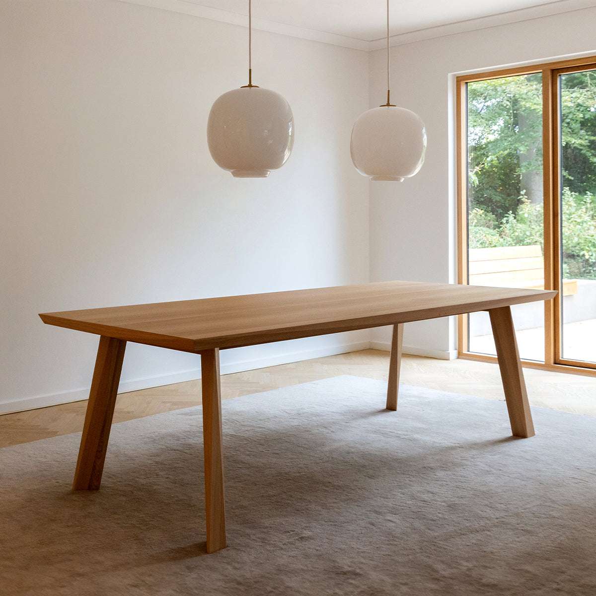 Rectangular European oak dining table with detailed facets, set indoors with matching chairs.