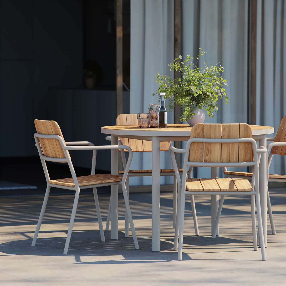 Round taupe Kirra Dining Table with teak wood top and powder-coated aluminum frame outdoors