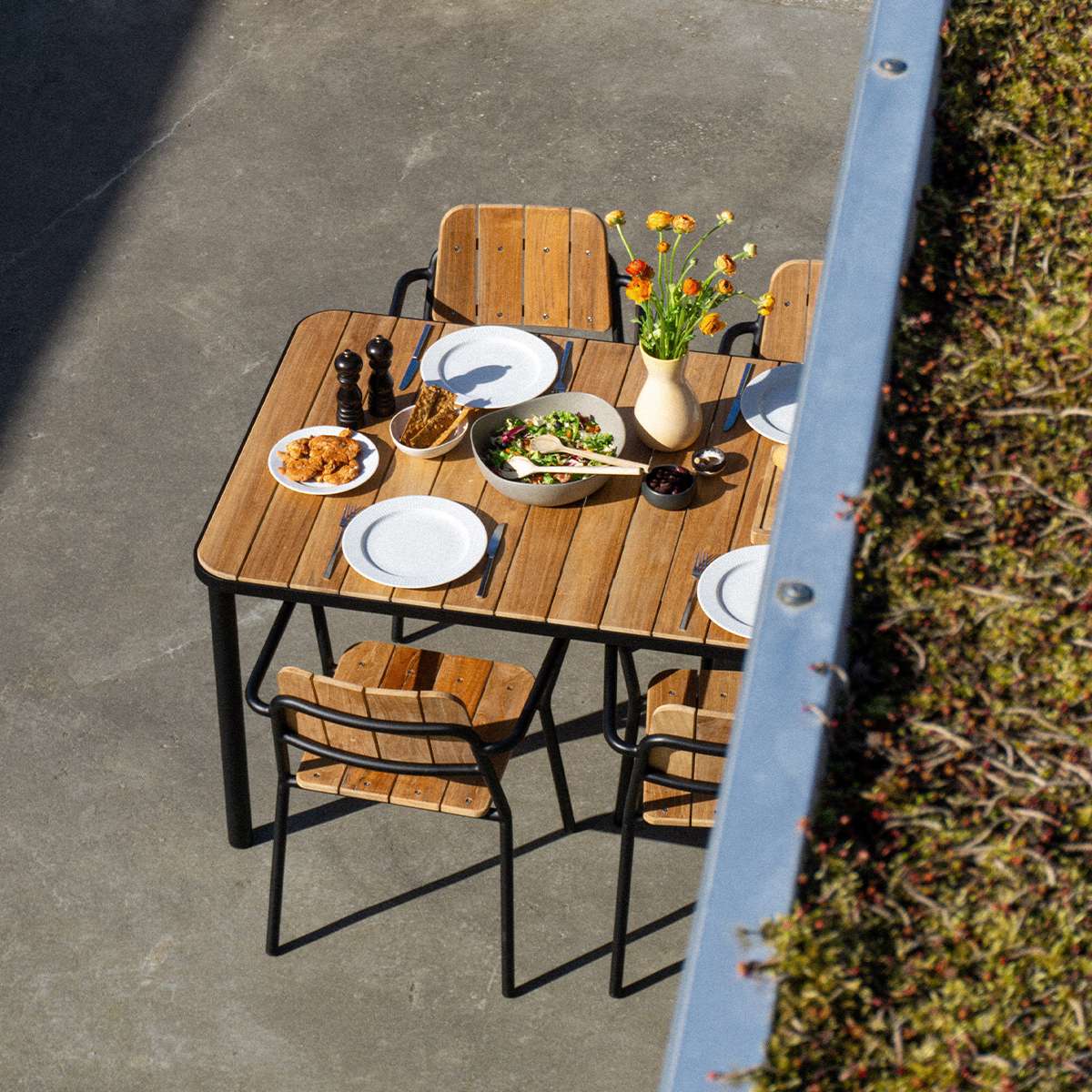 Kirra Dining Table 150x90 outdoor table with teak wood top and powder-coated aluminum frame in natural setting