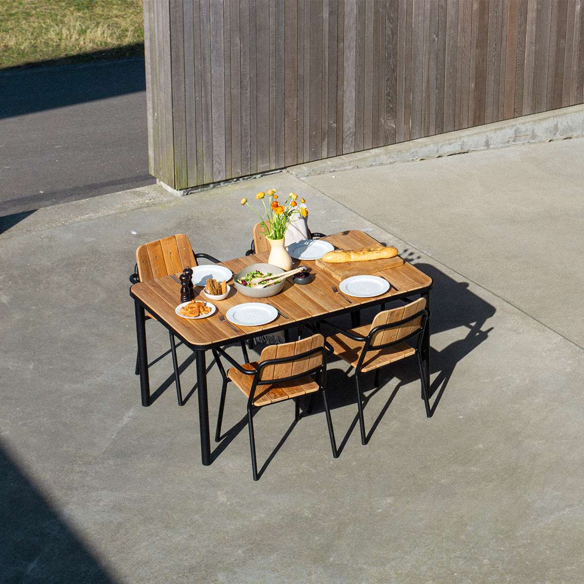 Kirra Dining Table 150x90 with teak wood top and powder-coated aluminum frame in outdoor setting