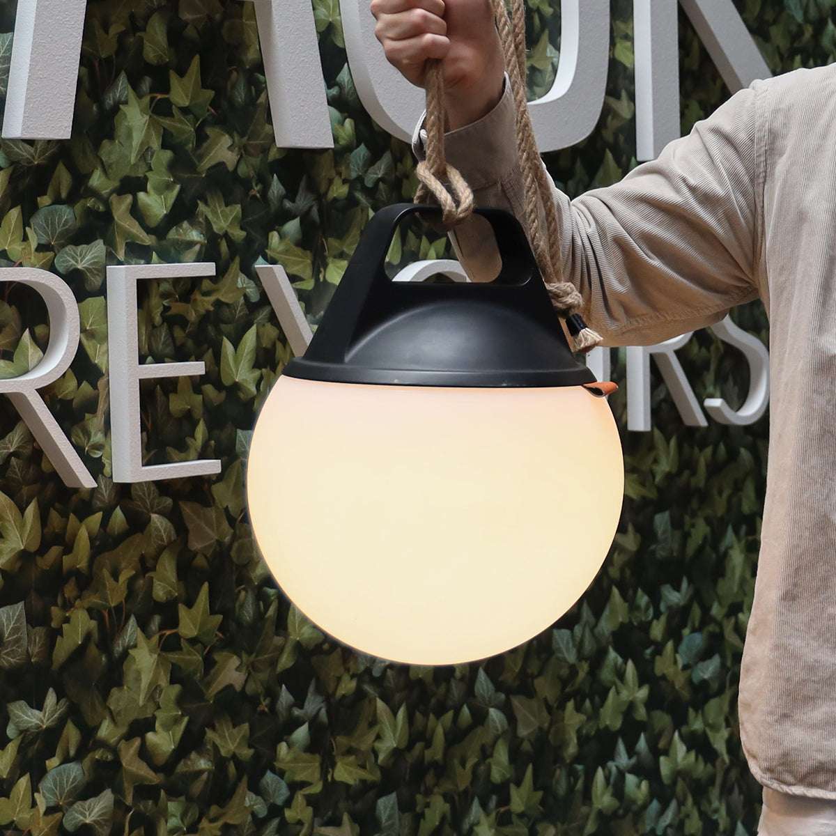 Two SACKit Light 250 outdoor lamps with white domes and hempen rope handles on a wooden surface outdoors