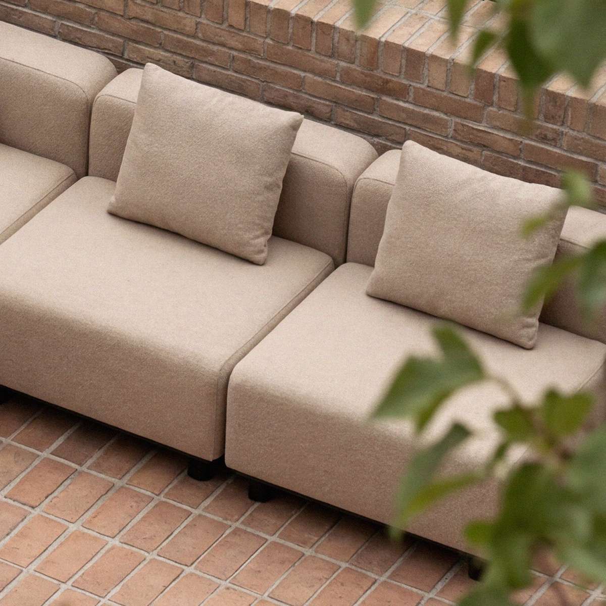 sackit Cobana modular outdoor sofa in warm beige with two cushions on a brick patio showcasing clean Scandinavian design and durable outdoor comfort