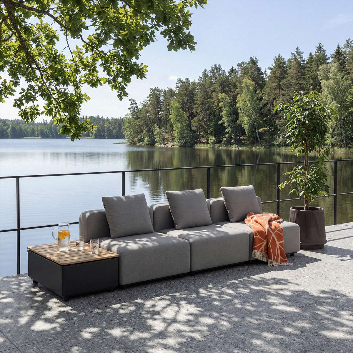 sackit modular outdoor lounge sofa in grey with cushions and side table on a lakeside terrace surrounded by trees and designed for Nordic weather