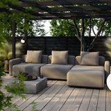 Outdoor three seat lounge sofa in warm gray with cushions on a timber deck beneath a pergola in a leafy garden designed by sackit