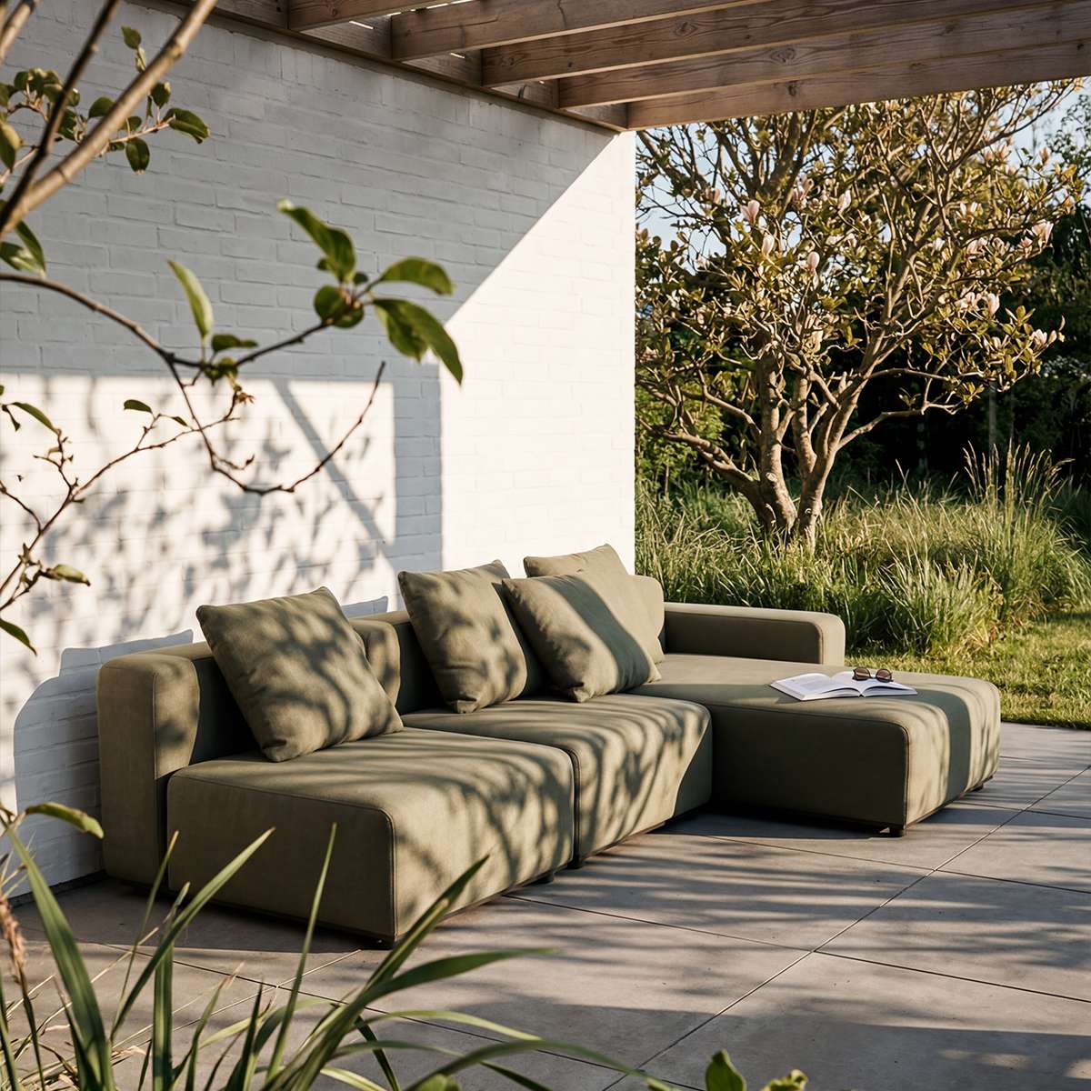 Olive green three seat chaise lounge sofa with cushions on a tiled patio beneath a pergola in a Scandinavian outdoor setting by sackit