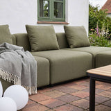 sackit olive green modular outdoor corner sofa with cushions and throw on a brick patio in a garden setting