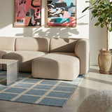 sackit Fjord Sofa with right chaise in a calm Scandinavian living room featuring framed art a potted tree and a blue geometric rug