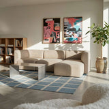 sackit Fjord sofa with right chaise in a bright Scandinavian living room with abstract art a wooden bookcase indoor plants and a blue geometric rug