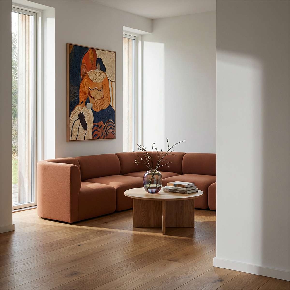 sackit Fjord corner sofa in warm brown fabric styled in a bright Scandinavian living room with a round wooden coffee table and colorful wall art