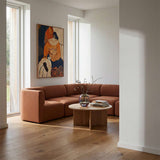 sackit Fjord corner sofa in warm brown fabric styled in a bright Scandinavian living room with a round wooden coffee table and colorful wall art