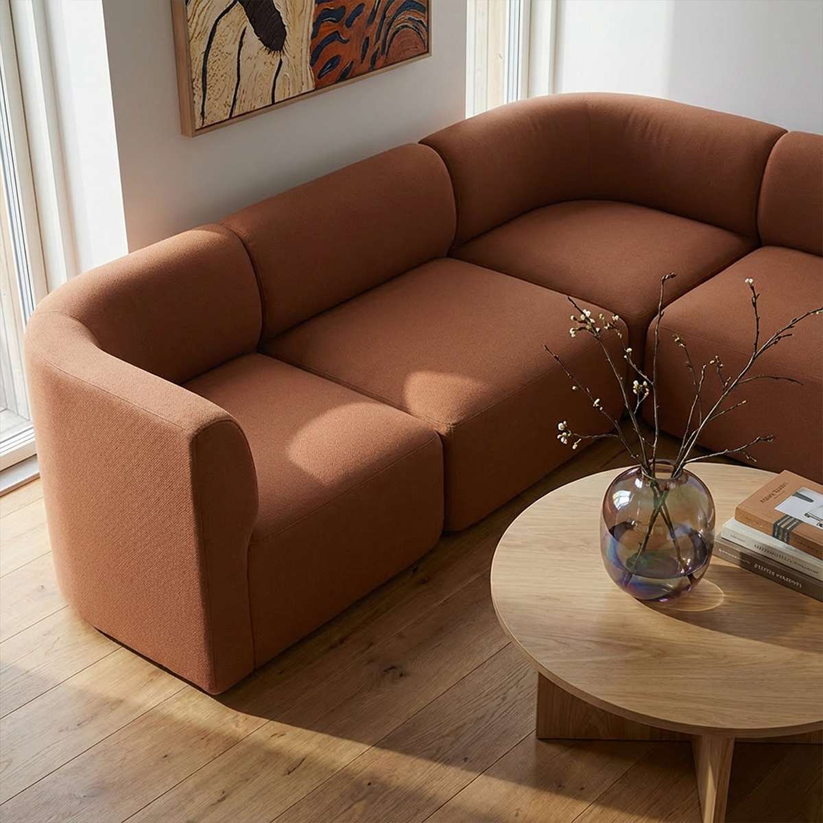 Brown Fjord corner sofa with soft rounded cushions in a bright Scandinavian living room beside a wooden coffee table with a glass vase from sackit
