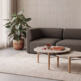 sackit Fjord two seater sofa in dark brown with round wood coffee tables and a leafy plant in a calm Scandinavian living room