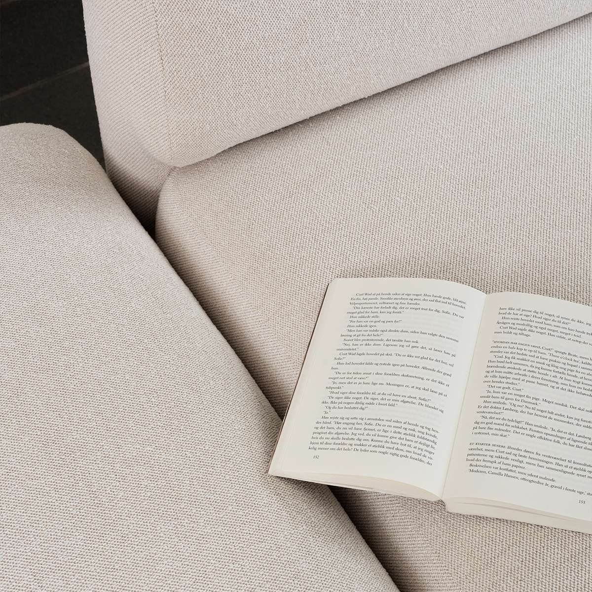 Open book resting on the soft textured cushions of a sackit Fjord corner sofa in a calm Scandinavian interior