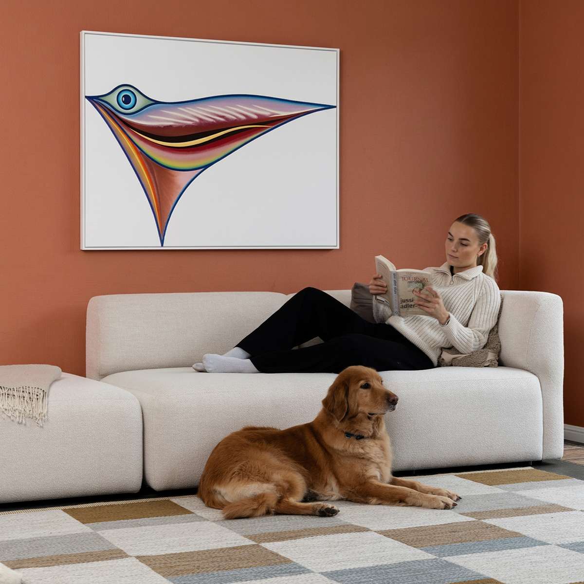 sackit Fjord two seat sofa with open end in a calm Scandinavian interior where a woman reads and a dog rests on the soft light upholstery
