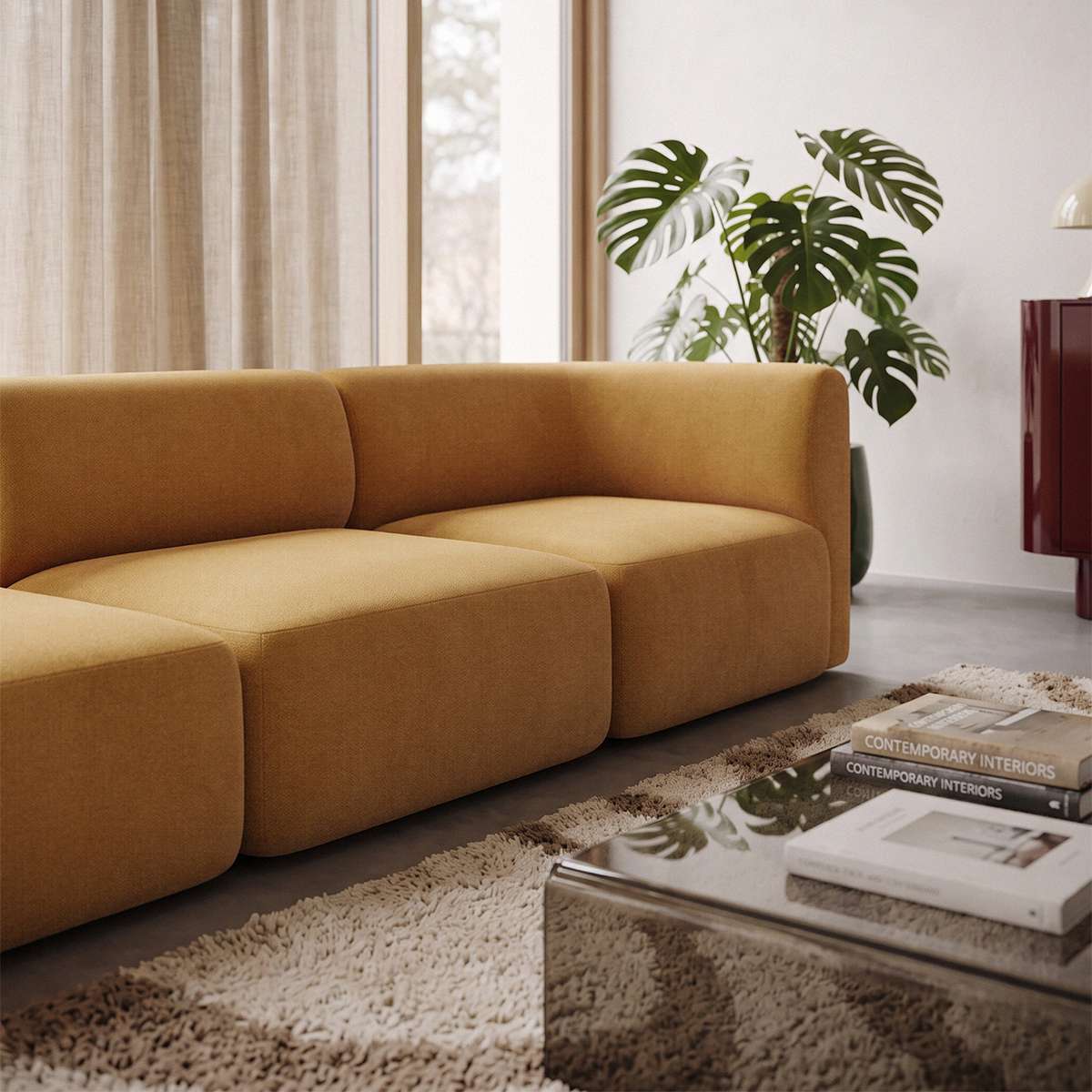 Curved three seater sofa in warm ochre upholstery styled in a calm Scandinavian living room with indoor plants and a glass coffee table by sackit