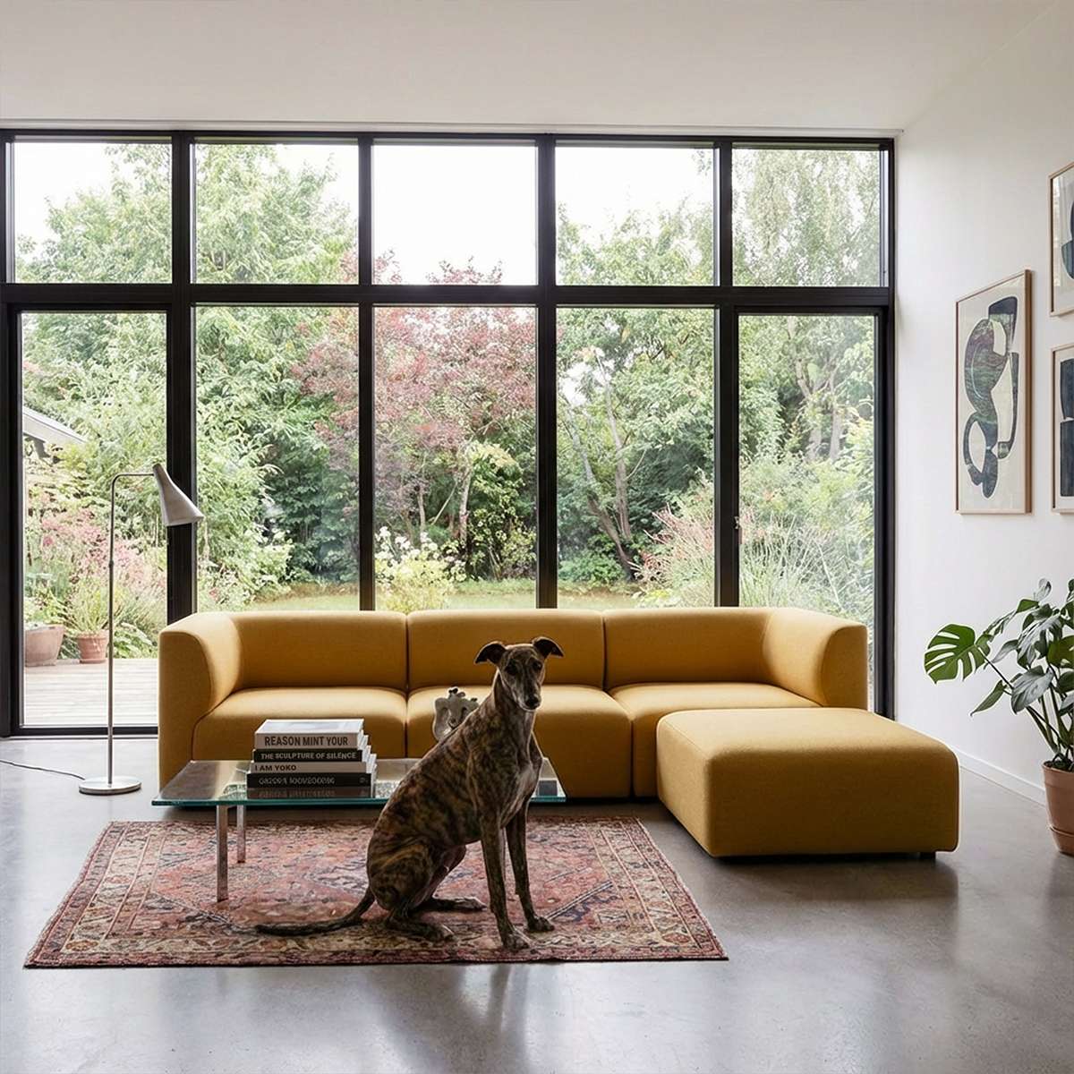 Mustard yellow sackit three seater sofa with chaise in a bright Scandinavian living room featuring a patterned rug large windows and a seated dog