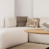 Cream Fjord corner sofa with textured neutral cushions in a calm Scandinavian living room beside a round wooden coffee table from sackit