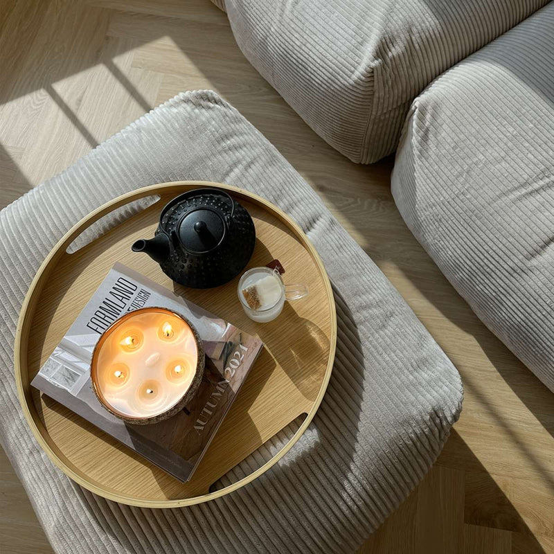 Round wooden serving tray with a natural oak finish and subtle integrated handles on a flat surface