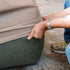 Hands fitting a sand water repellent cover over a green Soft Sofa outdoor seat to protect it from wind and weather with sackit design