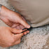 Hands fastening the drawstring on a sand weather resistant cover for a Cobana Lounge Sofa by sackit Europe