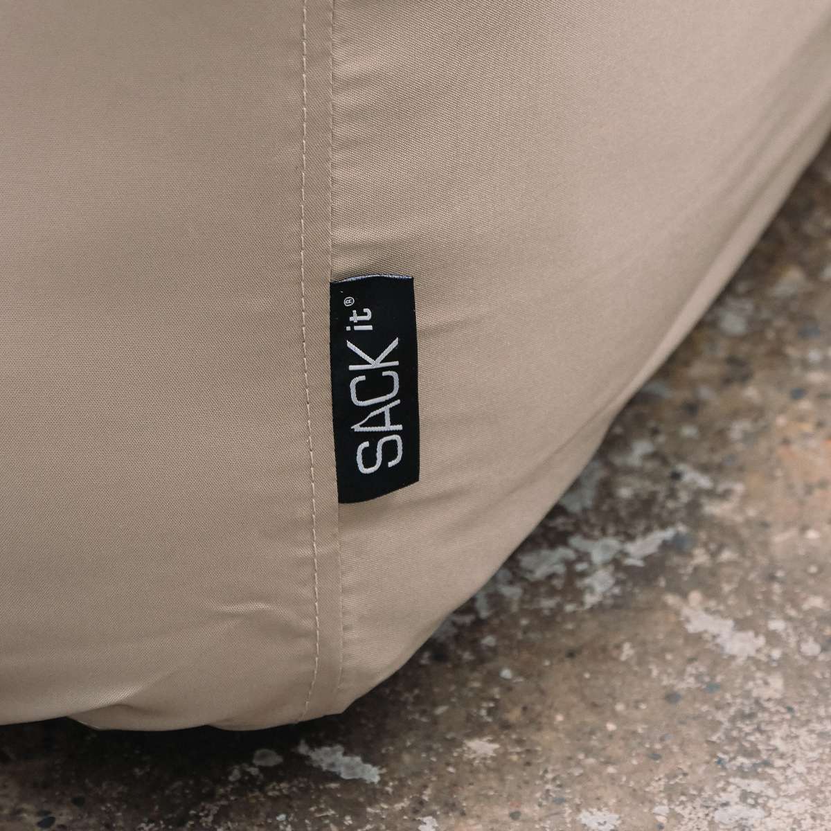 Close up of a sand colored water repellent cover for a Cobana Lounge Sofa with stitched seams and a black sackit label protecting outdoor furniture
