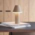 sackit cone cordless table lamp in warm beige resting on stacked books on a modern wooden table indoors