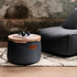 Dark gray sackit canvas pouf with a wooden tray holding books and headphones beside a matching lounge chair in a rustic indoor setting