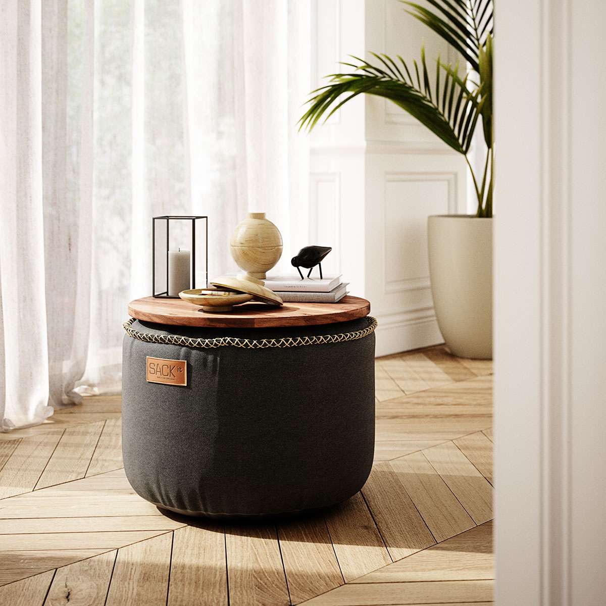 Black canvas pouf with a wooden tray top in a bright Nordic interior from sackit