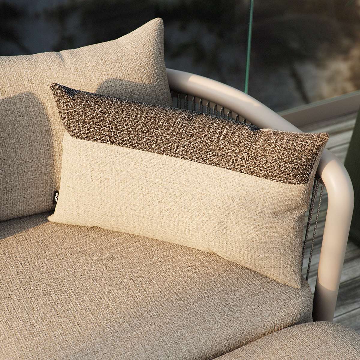 Sand and indigo color-blocked outdoor cushion with removable cover on a wooden surface