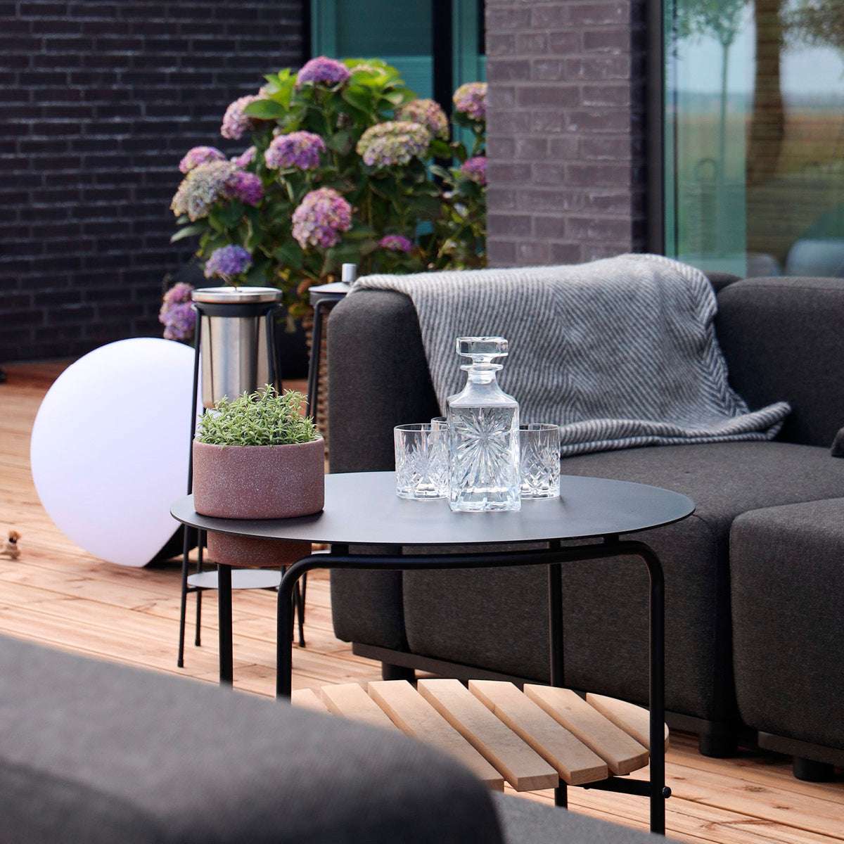 Outdoor patio sofa table with black powder-coated aluminum frame and teak wood shelf underneath