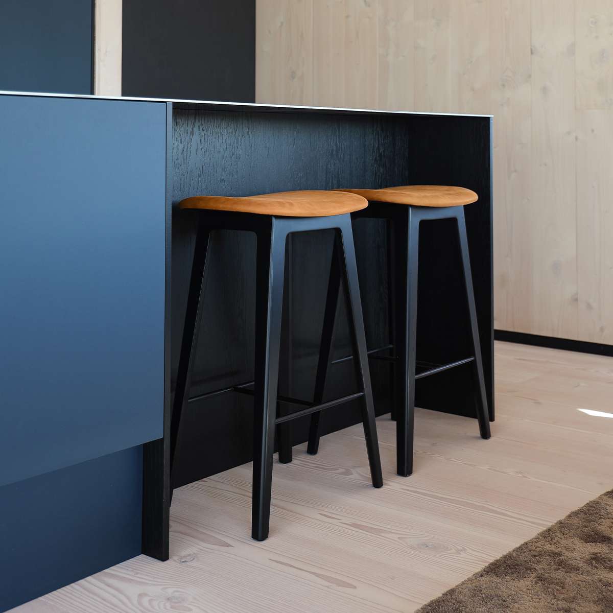 Nordic bar stool in black stained oak with Terra Black leather upholstery and steel footrest.