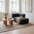 Dark gray Fjord chaise sofa with right side chaise and draped beige throw in a bright Scandinavian living room with a wood coffee table and woven rug by sackit