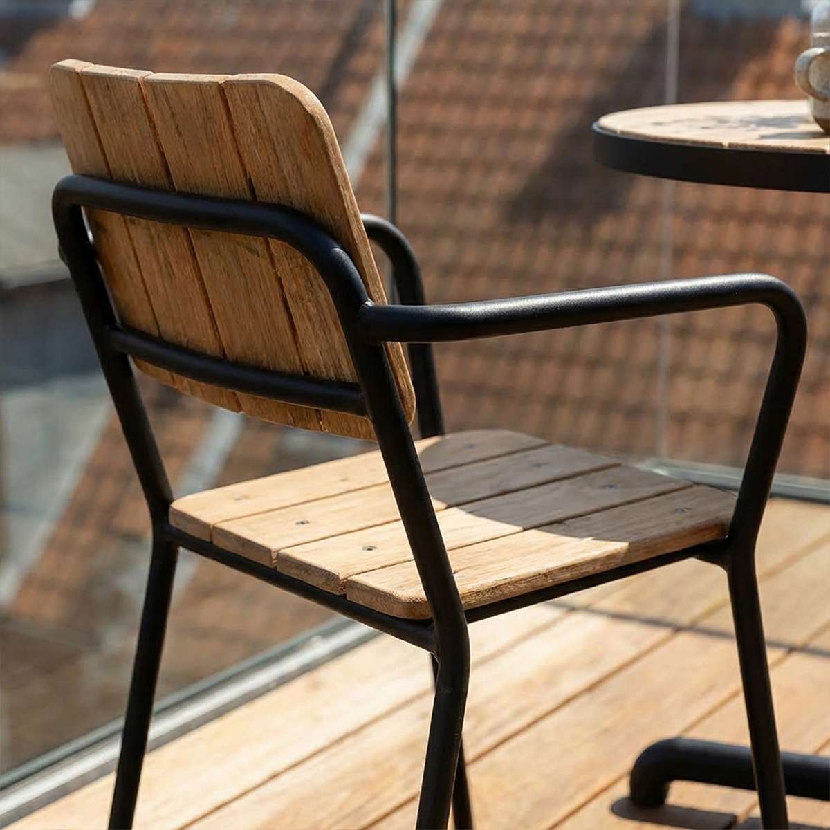 Kirra Patio Chair in black powder-coated aluminum and teak wood, outdoor setting.