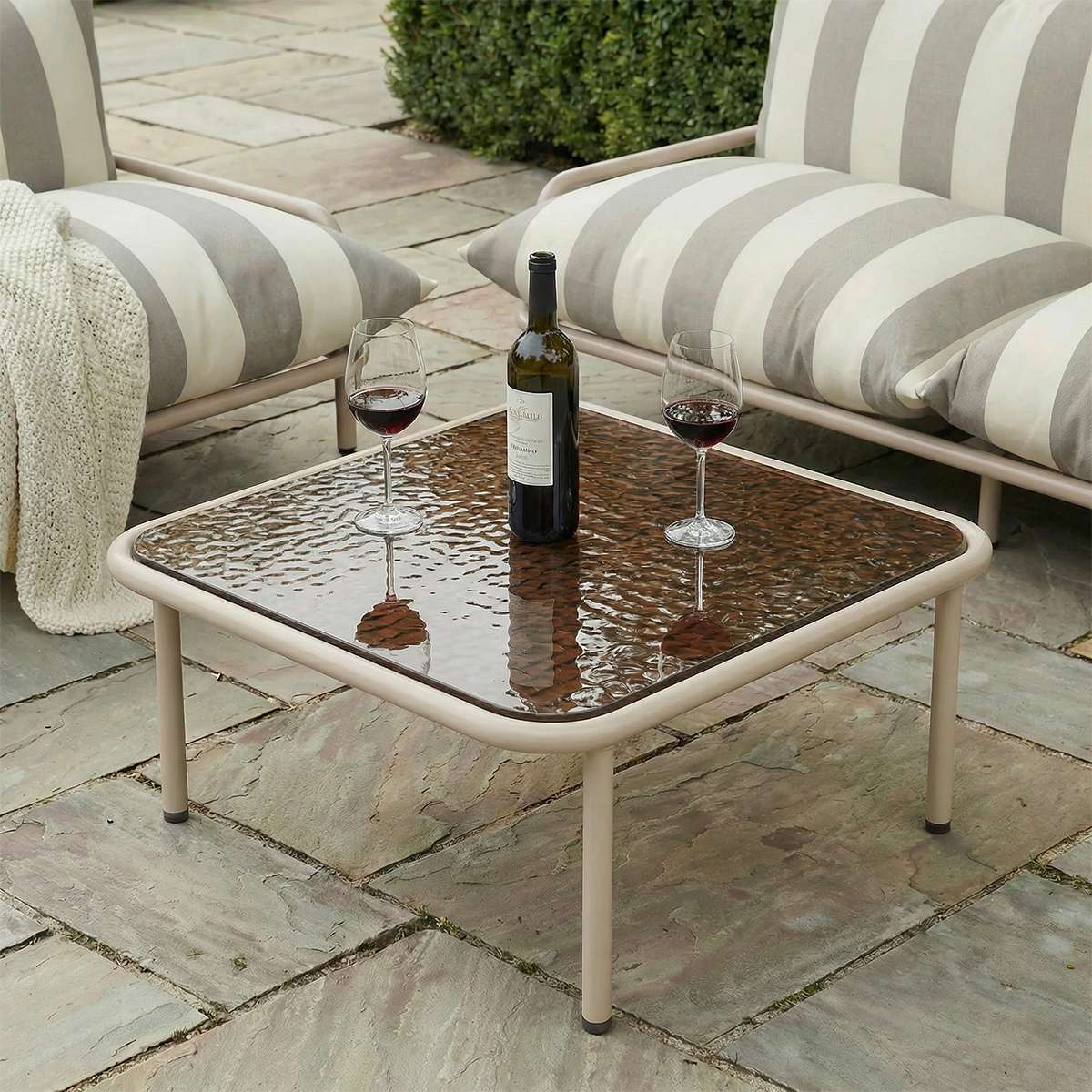 Square taupe Mollis Coffee Table with powder-coated aluminum frame and smoked tempered glass top outdoors.