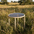 Taupe Mollis Side Table Ø50 with powder-coated aluminum frame and smoked tempered glass top outdoors